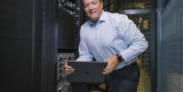 Chief Information Officer (CIO) poses in front of servers housing Lynn's data